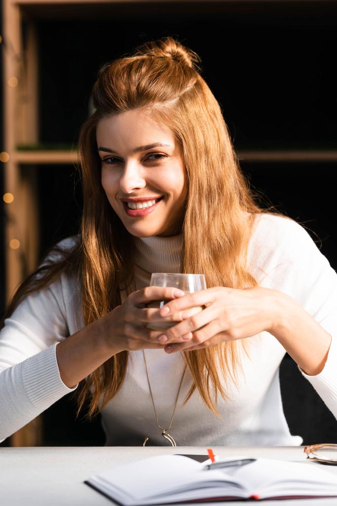 красивая улыбающаяся женщина держит стакан кофе в кафе
  - Фото, изображение