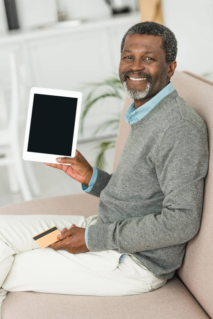uśmiechnięty Afroamerykanin trzymający kartę kredytową i pokazujący cyfrowy tablet z czystym ekranem - Zdjęcie, obraz