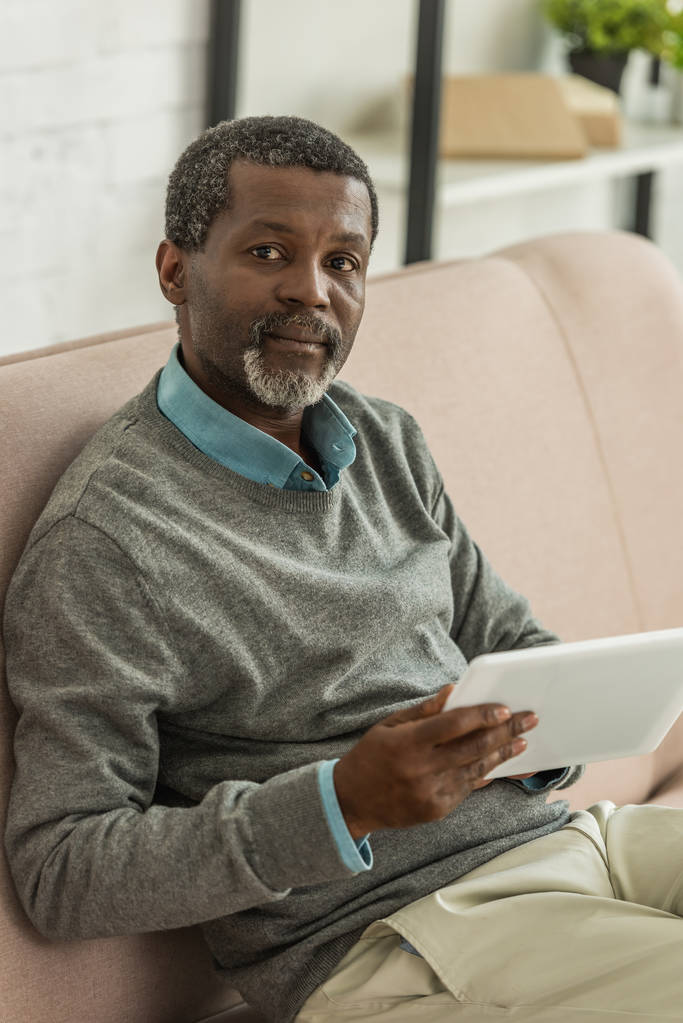 serious african american man holding digital tablet and looking at camera - 写真・画像