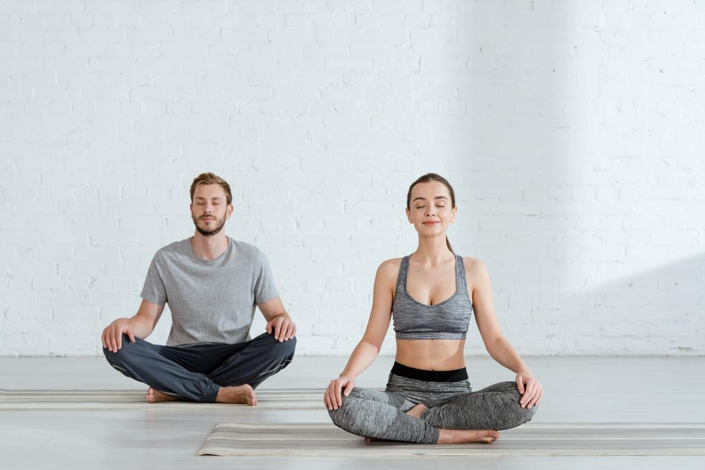 jovem homem e mulher praticando ioga em meia postura de lótus
 - Foto, Imagem