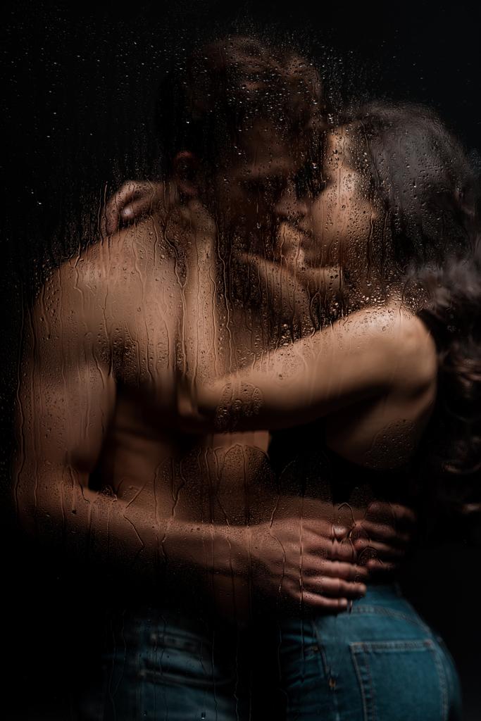 passionate couple hugging and kissing behind wet glass - Photo, Image