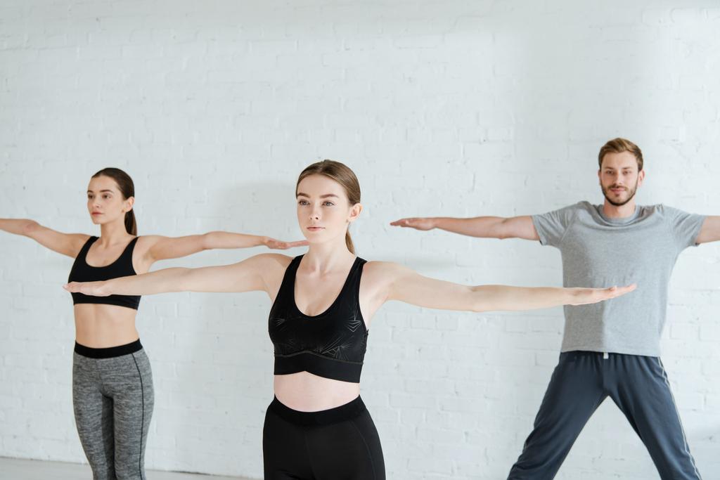 young men and woman practicing yoga in mountain open arm pose - Photo, Image