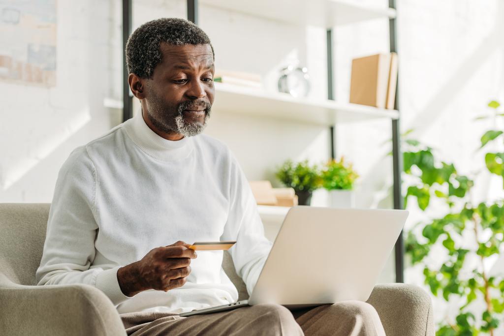 senior Afrikaans amerikaanse man met een creditcard tijdens het gebruik van laptop - Foto, afbeelding