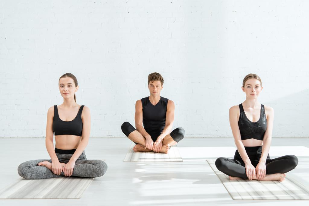 young women and man practicing yoga in half lotus pose - Photo, Image