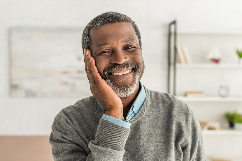 heureux afro-américain homme tenant la main près du visage tout en souriant à la caméra
 - Photo, image