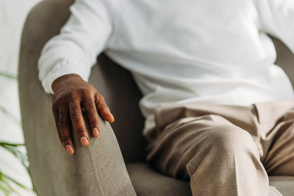 vista cortada do homem americano afican sênior sentado na poltrona
 - Foto, Imagem