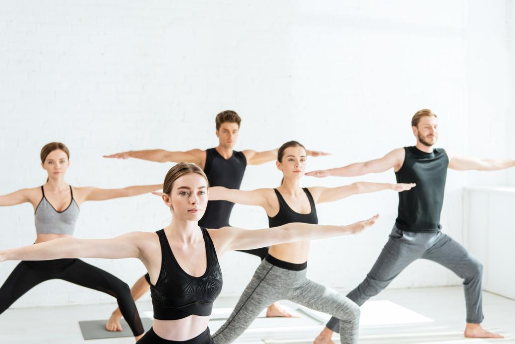 vijf jonge mensen beoefenen yoga in krijger Ii pose  - Foto, afbeelding