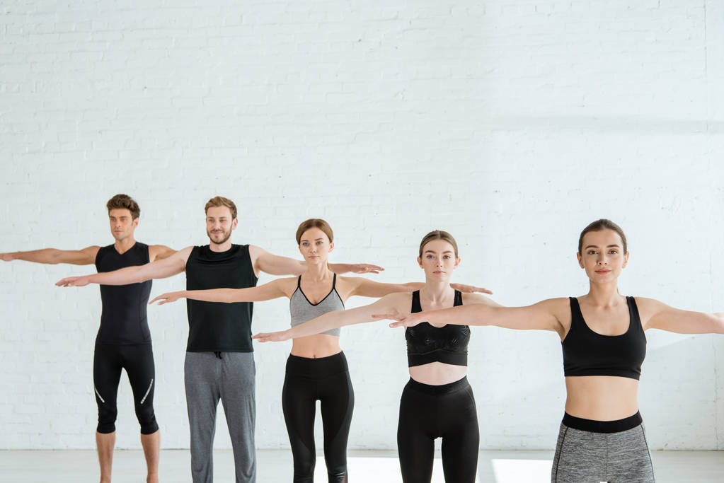 vijf jonge mannen en vrouwen beoefenen yoga in berg open arm pose - Foto, afbeelding