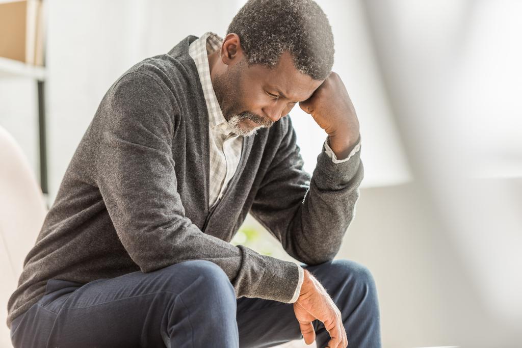 szelektív fókusz depressziós afro-amerikai férfi ül lehajtott fejjel - Fotó, kép