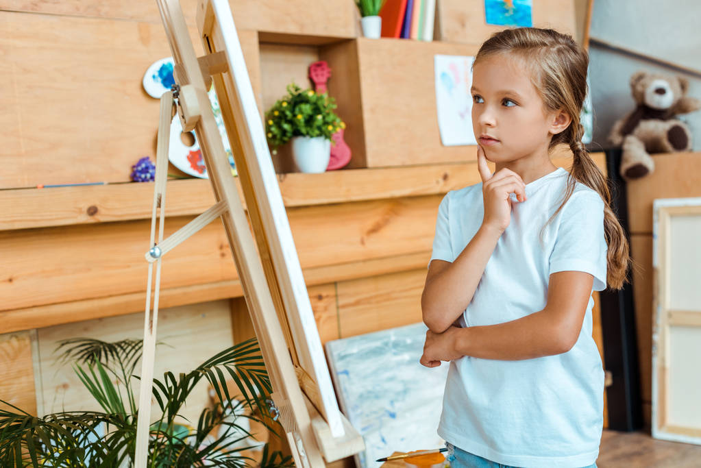 pensive kid looking at easel in art school  - Photo, Image