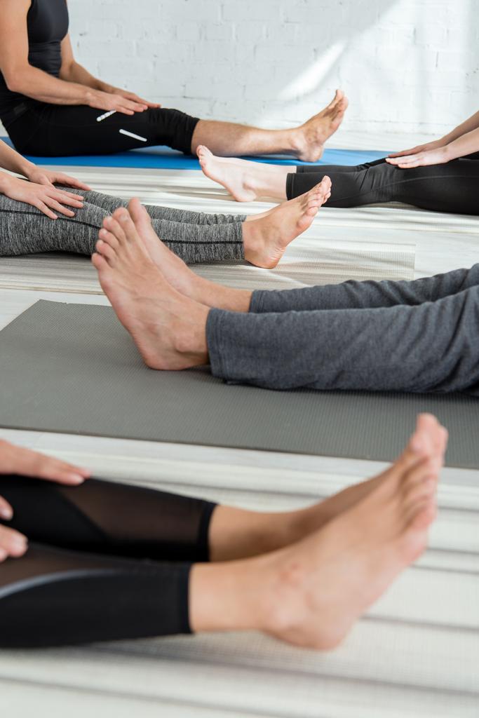 vista ritagliata di persone a piedi nudi seduti su stuoie yoga in posa personale
 - Foto, immagini