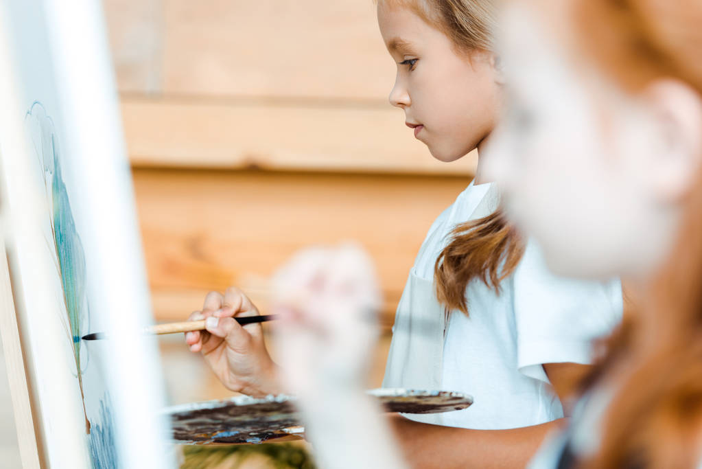 selective focus of adorable kid painting on canvas near child - Photo, Image