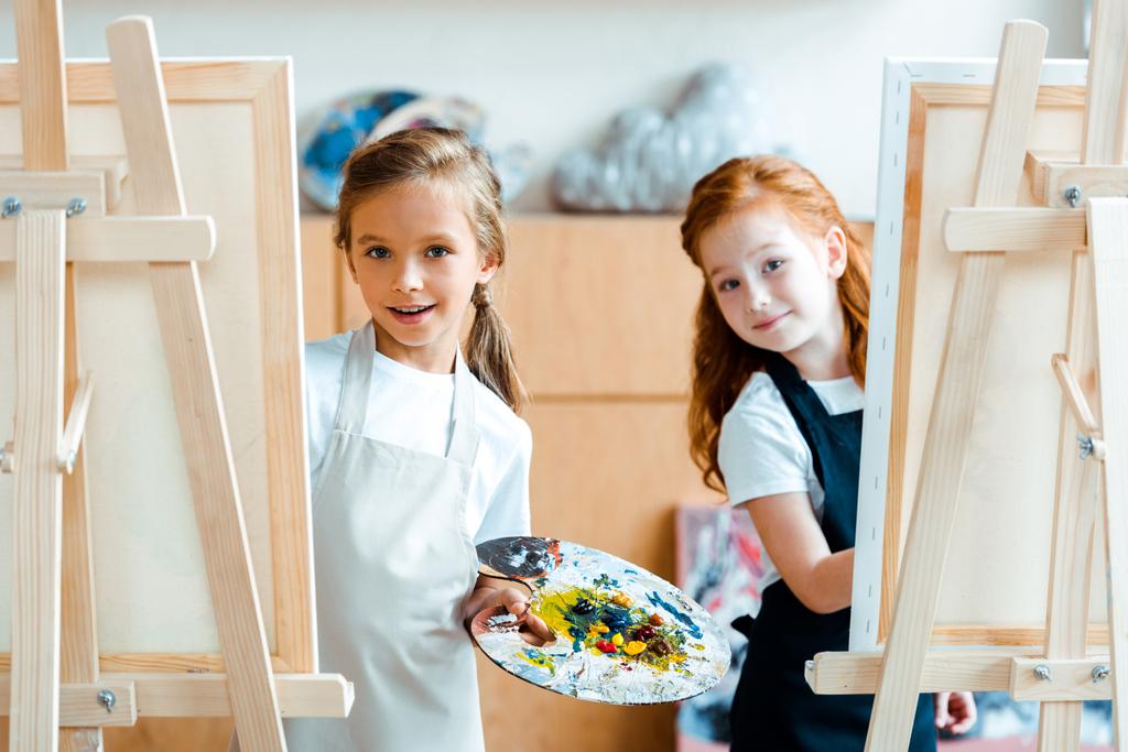selective focus of adorable kids standing near easels  - Photo, Image