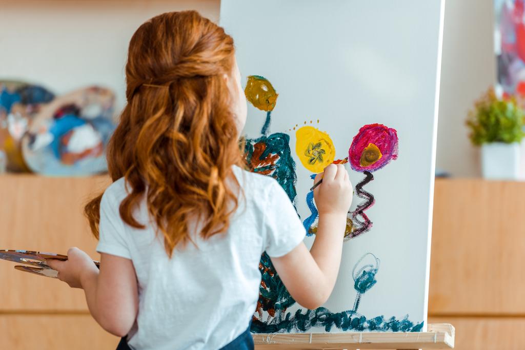 vista posterior de la pintura infantil pelirroja sobre lienzo en la escuela de arte
  - Foto, Imagen