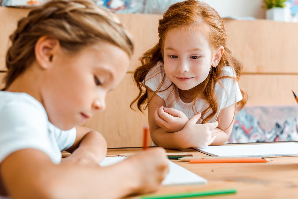 селективное внимание милого рыжего ребенка, смотрящего на очаровательный детский рисунок на бумаге
  - Фото, изображение