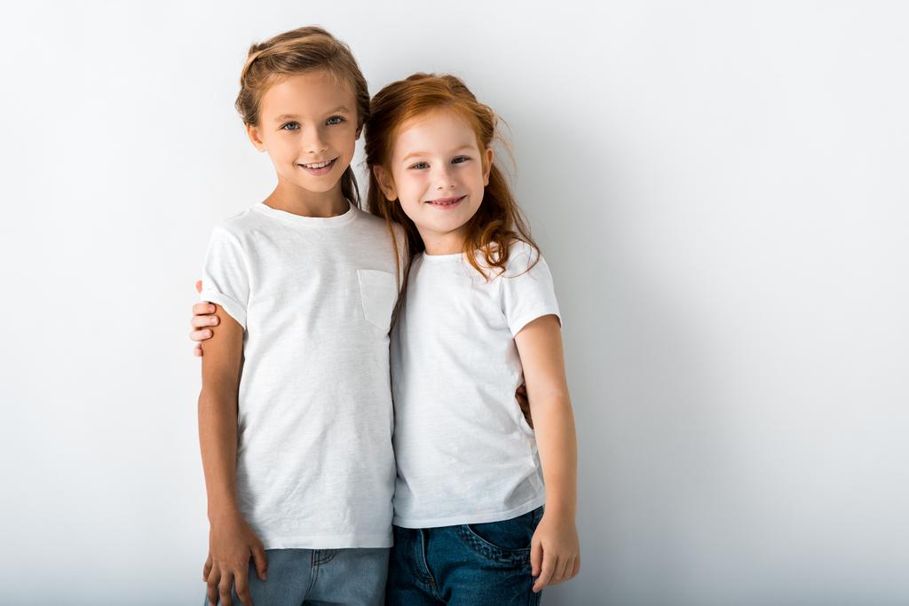 radosne dzieci przytulają się stojąc na białym  - Zdjęcie, obraz