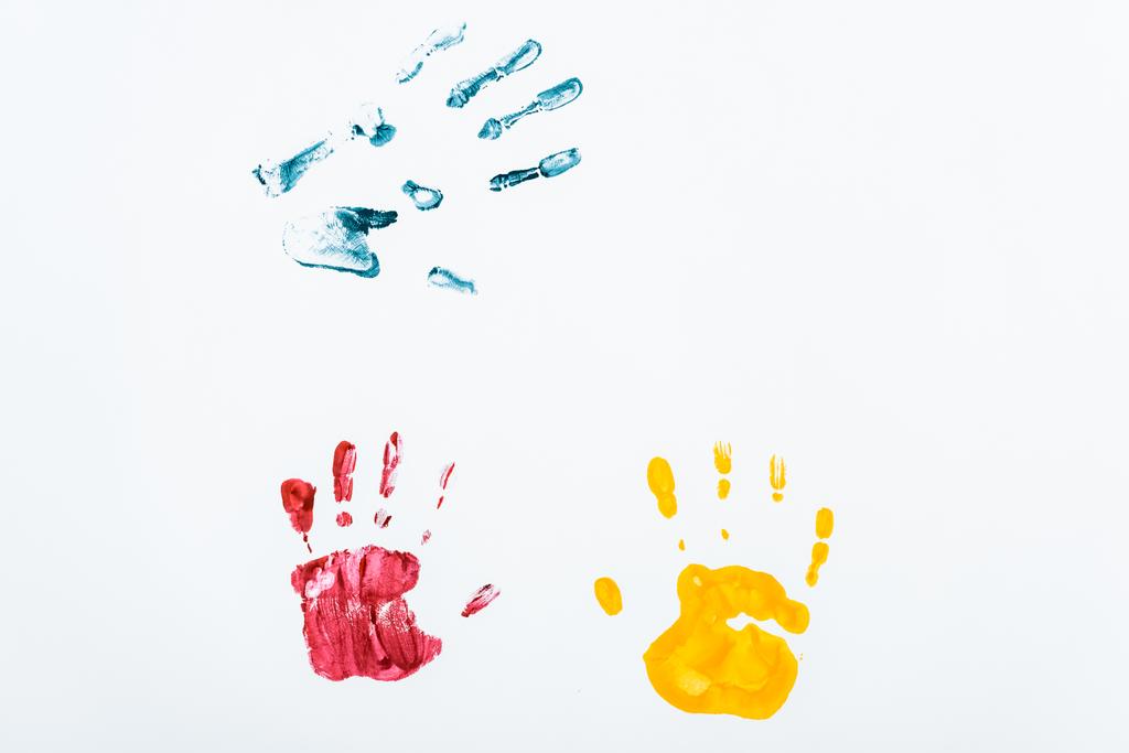 rode, blauwe en gele handafdrukken op wit  - Foto, afbeelding