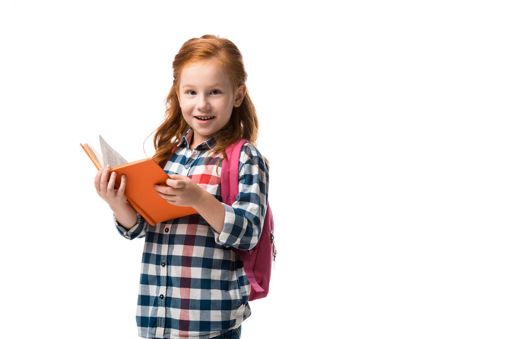χαρούμενο κοκκινομάλλικο παιδί που κρατάει πορτοκαλί βιβλίο απομονωμένο στα λευκά  - Φωτογραφία, εικόνα