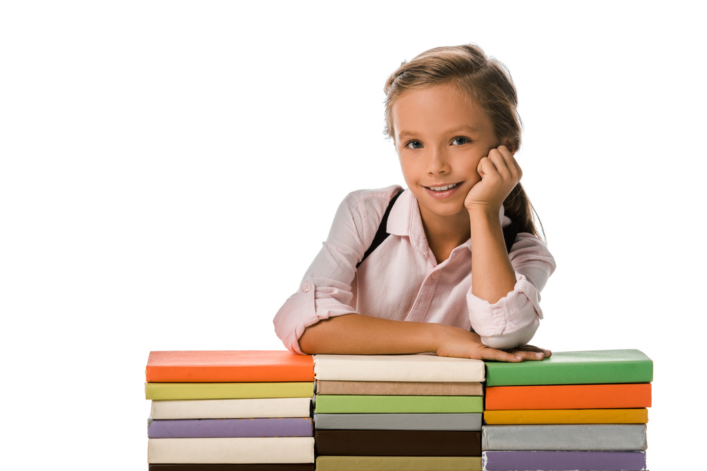 веселый ученик улыбается, глядя в камеру рядом красочные книги изолированы на белом
  - Фото, изображение