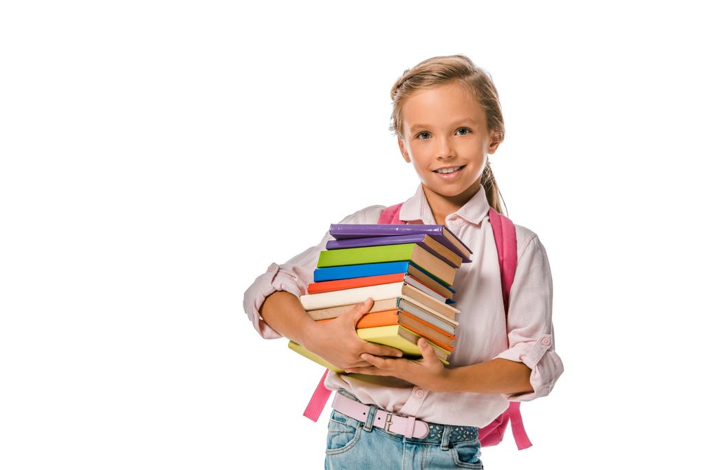 χαρούμενο σχολιαρόπαιδο κρατώντας πολύχρωμα βιβλία απομονωμένα στα λευκά  - Φωτογραφία, εικόνα