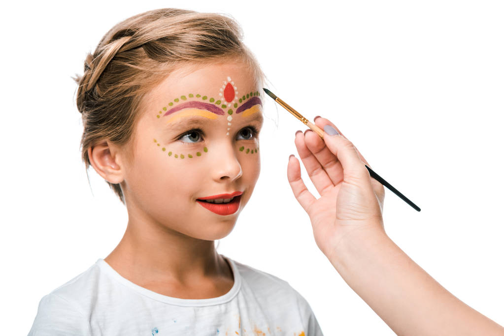 vista recortada de la mujer sosteniendo pincel cerca de niño lindo con pintura de la cara aislado en blanco
  - Foto, Imagen