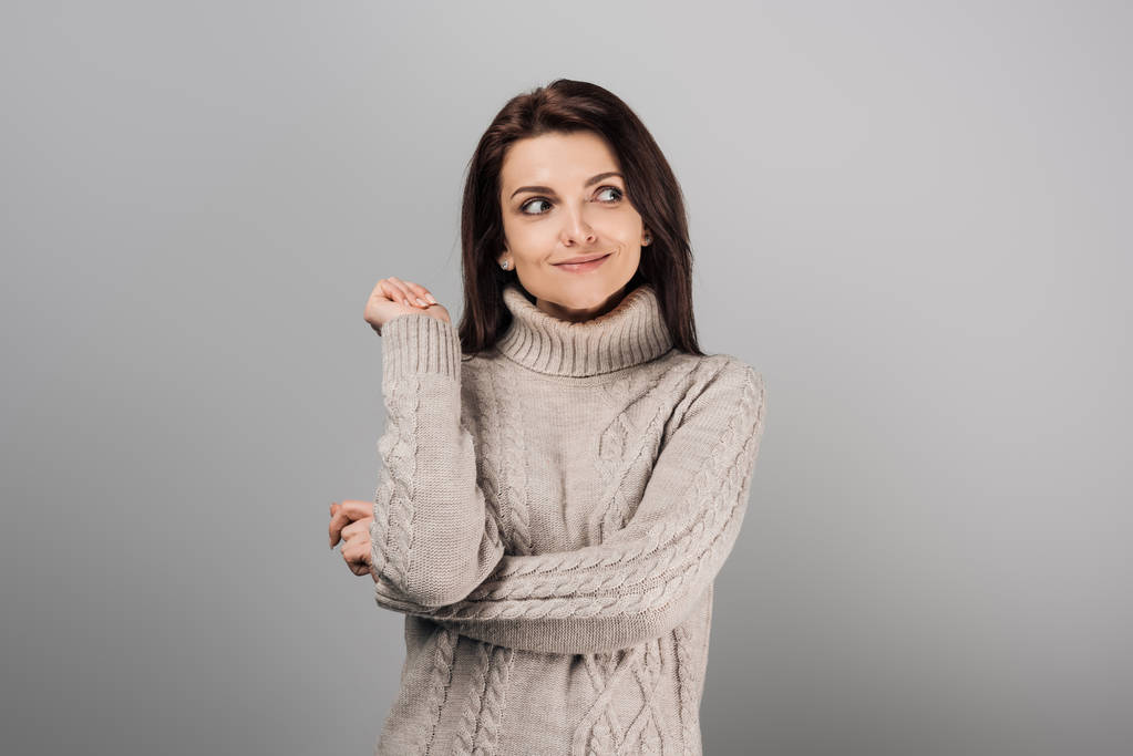 mujer alegre en suéter mirando hacia otro lado aislado en gris
  - Foto, imagen