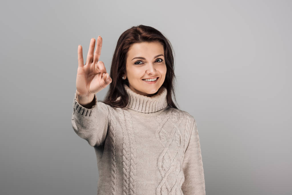 alegre mujer en suéter mostrando ok signo aislado don gris
  - Foto, Imagen