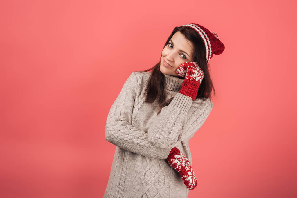 cheerful woman in red knitted hat and gloves looking at camera on pink  - Photo, Image