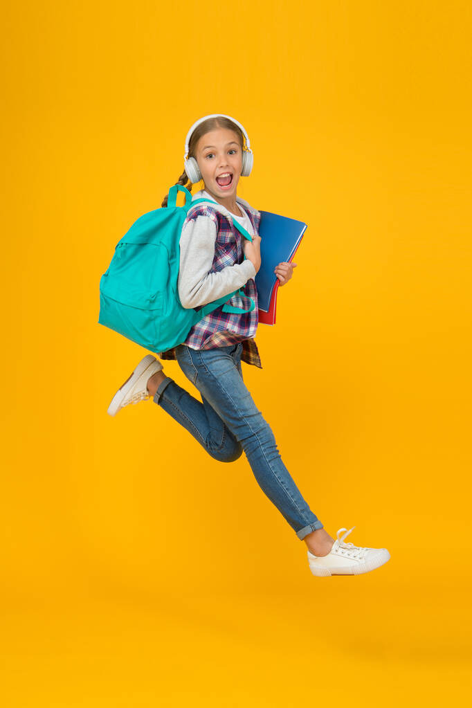 Getting back into studying. Energetic little girl run to school yellow background. Small child with school bag and books back to class. Back to school time. Happy welcome back - Photo, Image
