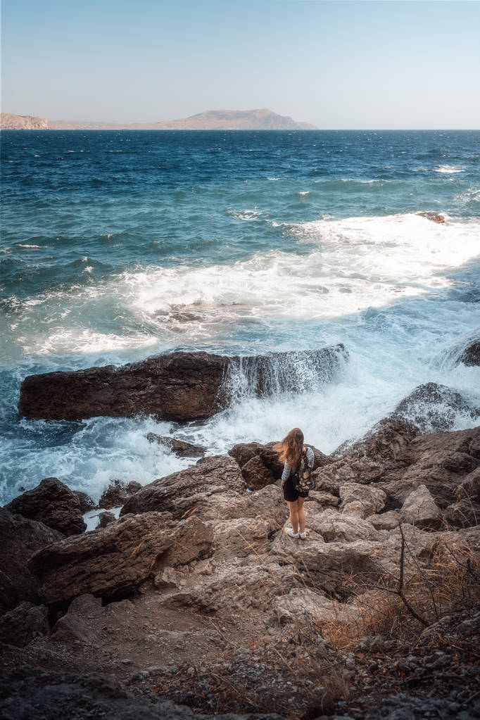 Νεαρό όμορφο κορίτσι στέκεται στην παραλία και κοιτάζει τα κύματα. Ταχυδρομική κάρτα - Φωτογραφία, εικόνα