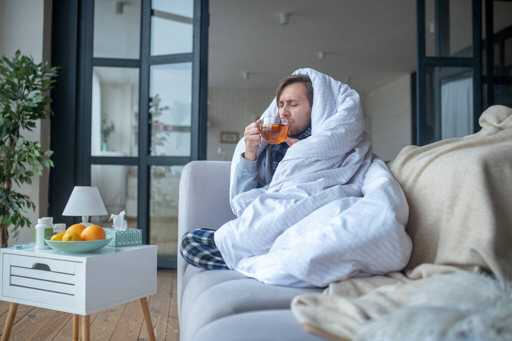 Nemocný muž tráví den v obývacím pokoji při pití čaje - Fotografie, Obrázek