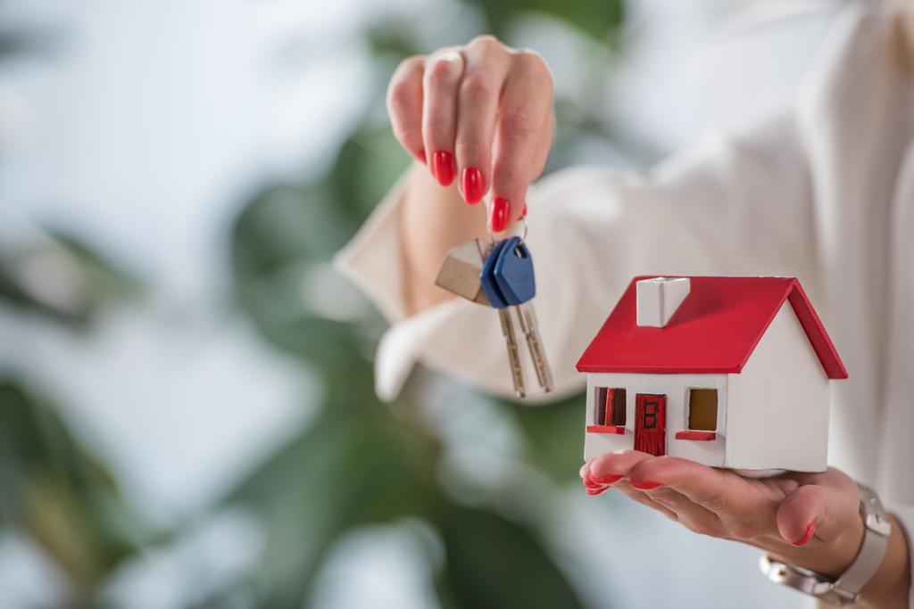 partial view of businesswoman showing house model and keys  - Photo, Image