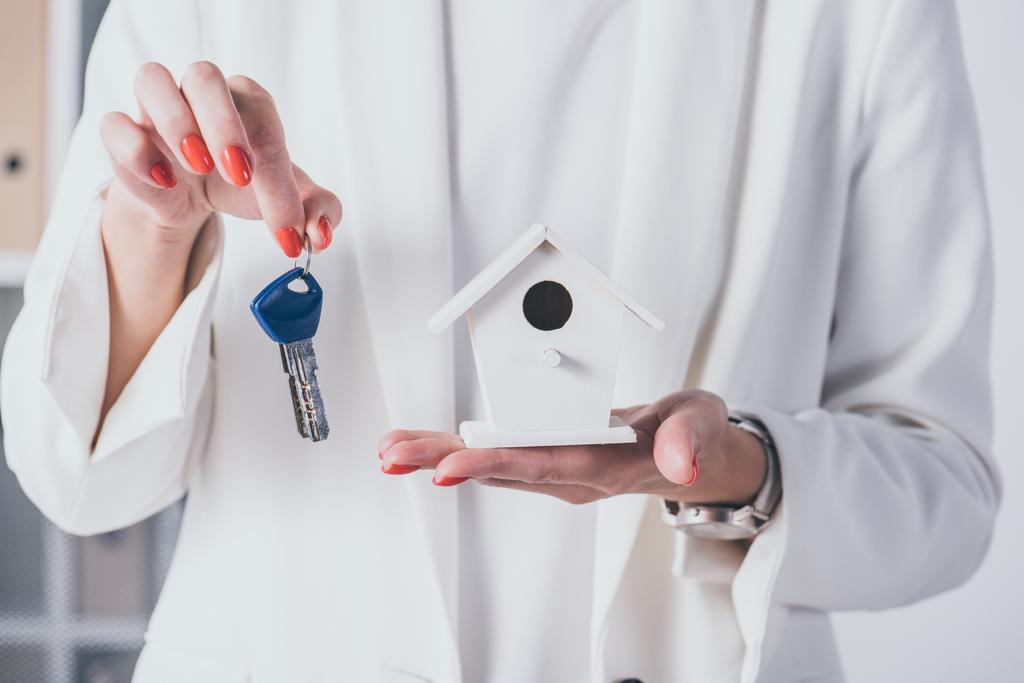 częściowy widok businesswoman pokazuje model domu i klucze - Zdjęcie, obraz