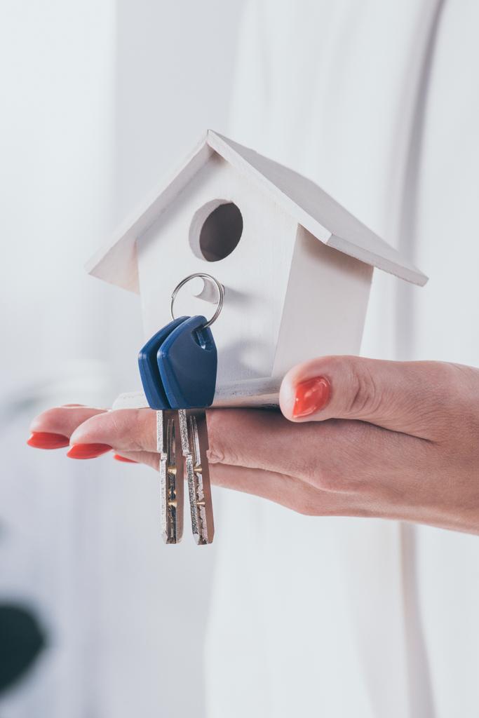 частичный взгляд предпринимательницы, держащей модель дома с ключами
 - Фото, изображение