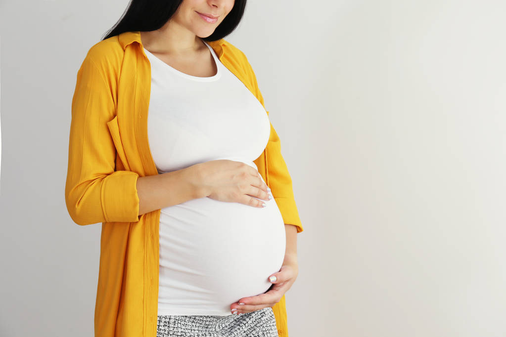 Młoda kobieta trzymająca brzuch ciężarnej w dziewiątym miesiącu ciąży. - Zdjęcie, obraz