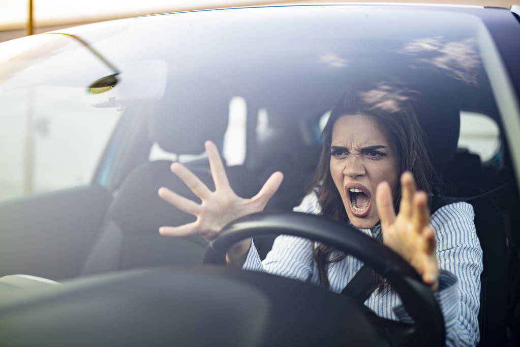 Gestresste Autofahrerin sitzt in ihrem Auto. Wütende Autofahrerin. Wütende junge Frau steckt im Stau fest. Frau im Auto genervt. Mädchen steckt im Verkehr fest. - Foto, Bild