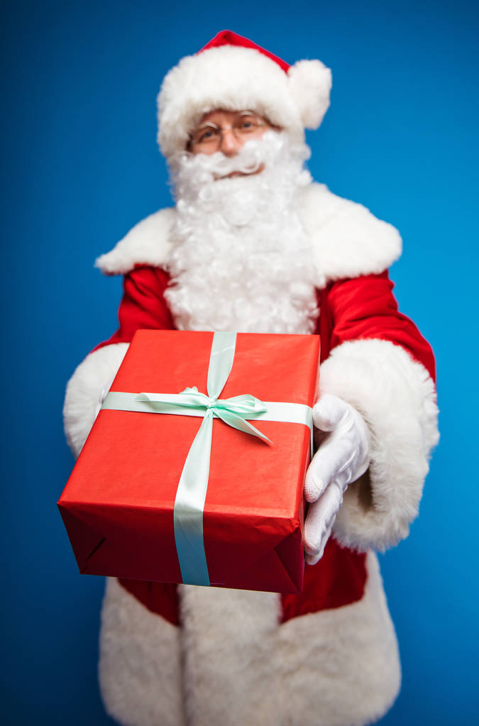  Weihnachts- und Neujahrskonzept. Porträt eines Mannes im Weihnachtsmann-Kostüm mit Geschenk - Foto, Bild