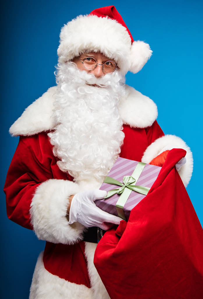  Weihnachts- und Neujahrskonzept. Porträt eines Mannes im Weihnachtsmann-Kostüm mit Geschenk - Foto, Bild