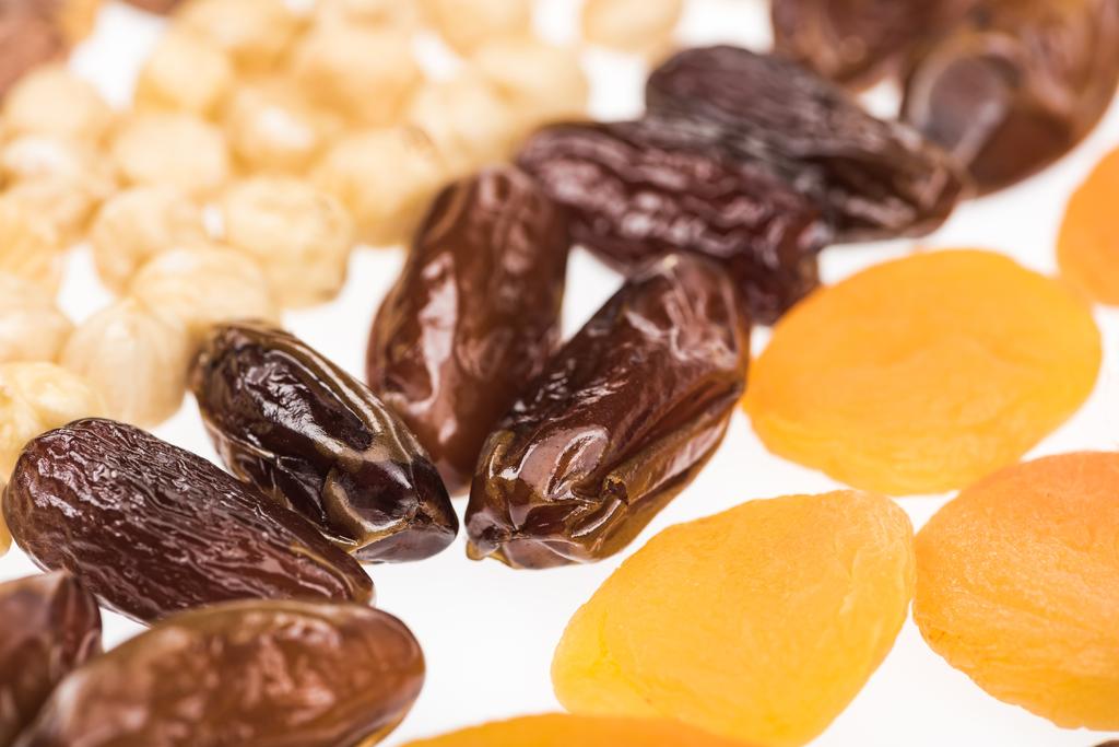 close-up zicht op gedroogde abrikozen, dadels en hazelnoot geïsoleerd op wit - Foto, afbeelding