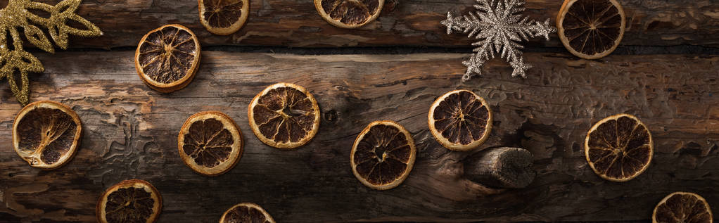 vista superior de fatias de citrinos secos e flocos de neve decorativos em fundo de madeira, tiro panorâmico
 - Foto, Imagem