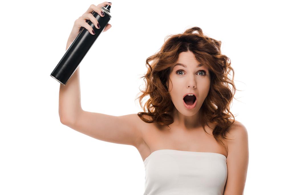 wstrząśnięty kręcone dziewczyna trzymając włosy spray butelka odizolowana na biały  - Zdjęcie, obraz