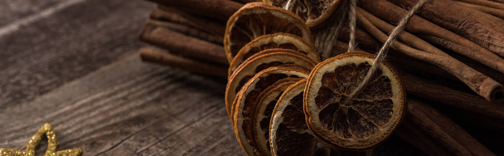 dried orange slices on thread and cinnamon on wooden background, panoramic shot - Photo, Image