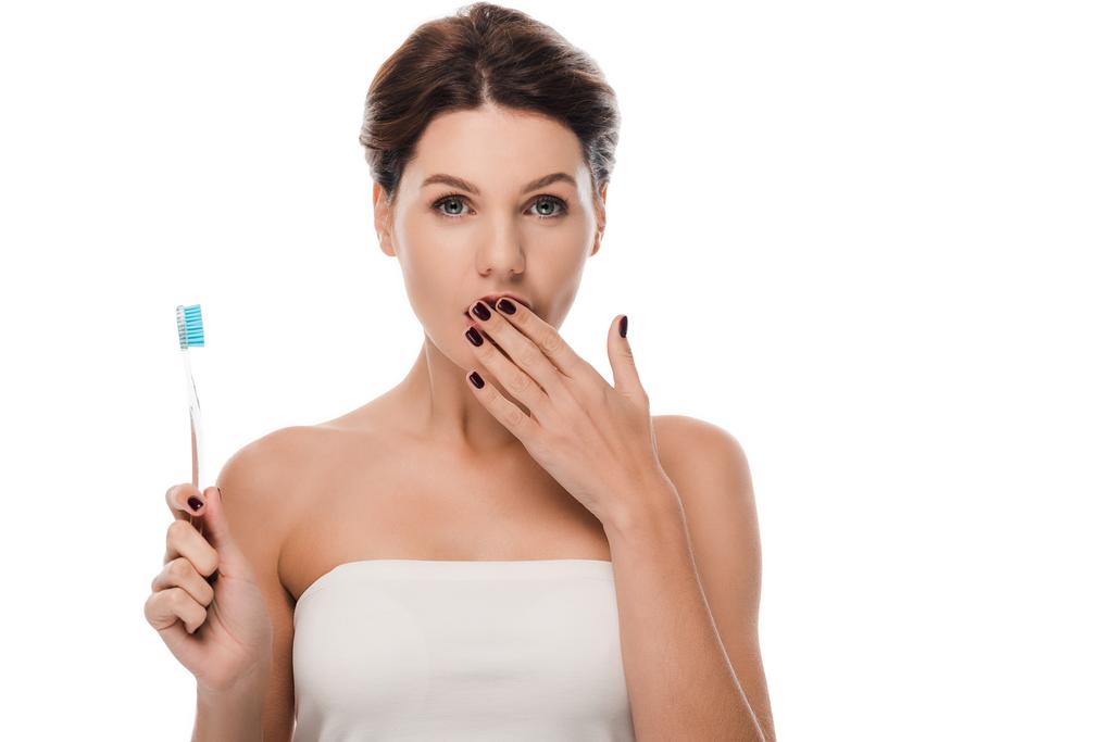 mulher chocada cobrindo boca e segurando escova de dentes isolada em branco
  - Foto, Imagem