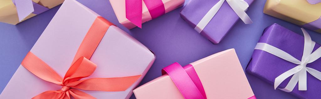 Draufsicht auf bunte Geschenke mit Schleifen auf violettem Hintergrund, Panoramaaufnahme - Foto, Bild