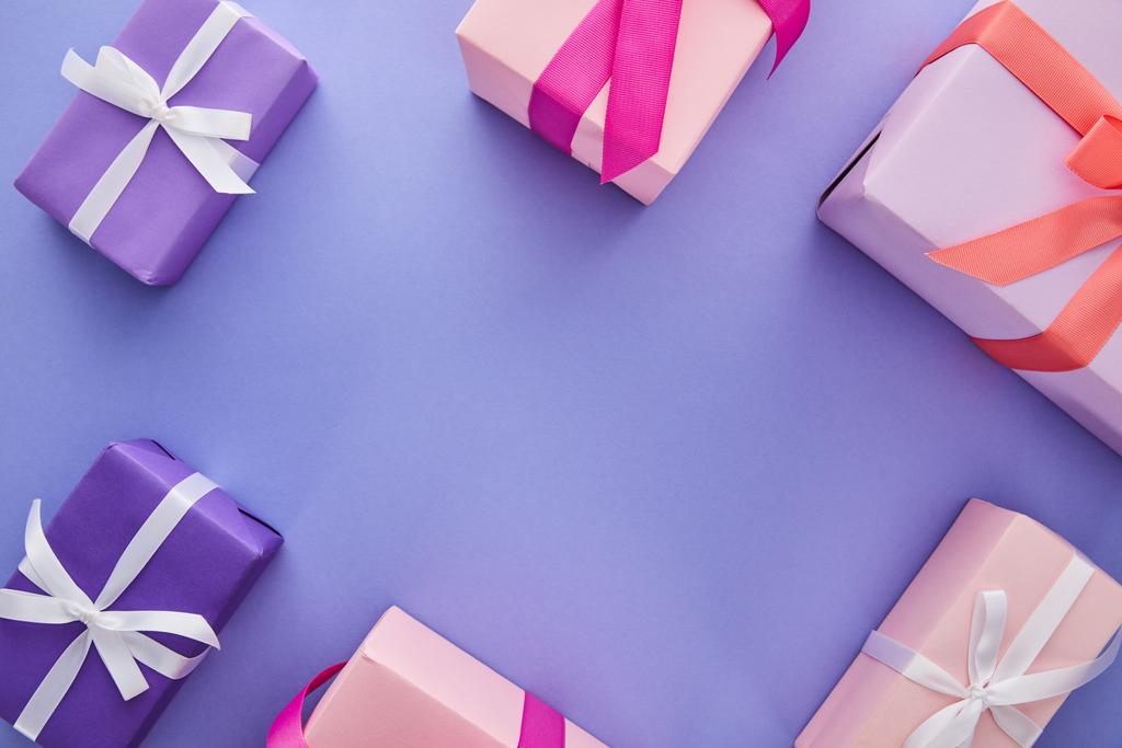 вид сверху красочных подарков с бантами на фиолетовом фоне с копировальным пространством
 - Фото, изображение