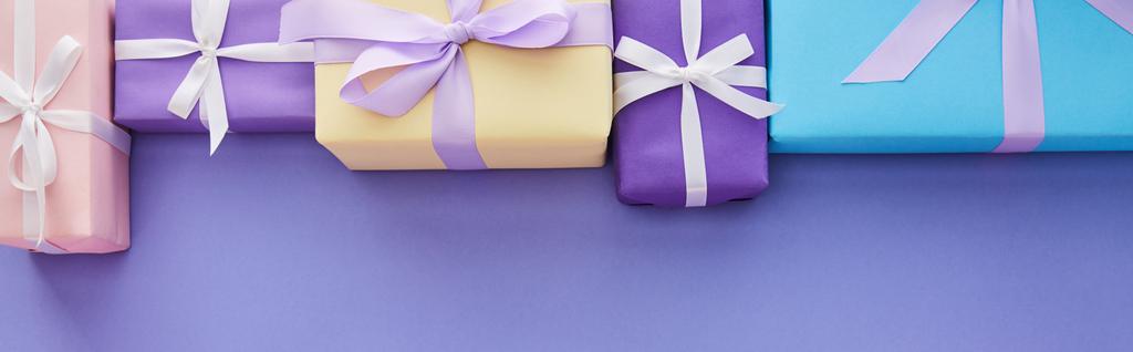 紫色の背景にコピースペース、パノラマショットで弓とカラフルな贈り物でフラットレイアウト - 写真・画像