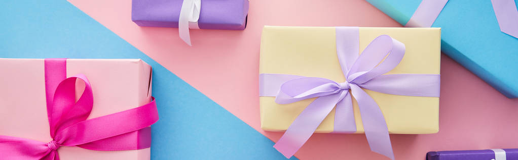 top view πολύχρωμα κουτιά δώρων με κορδέλες και φιόγκους σε μπλε και ροζ φόντο, πανοραμική λήψη - Φωτογραφία, εικόνα