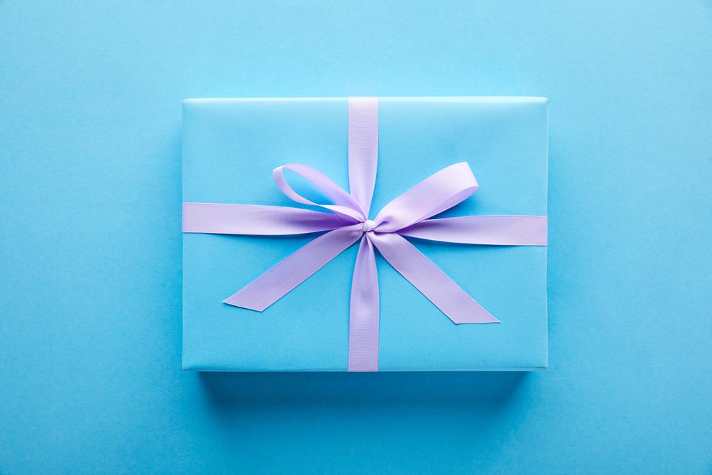 Mavi arkaplanda mor kurdeleli mavi hediye manzarası - Fotoğraf, Görsel