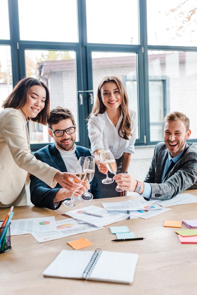 enfoque selectivo de empresarios y empresarios multiculturales felices sosteniendo copas de champán en la oficina
   - Foto, Imagen