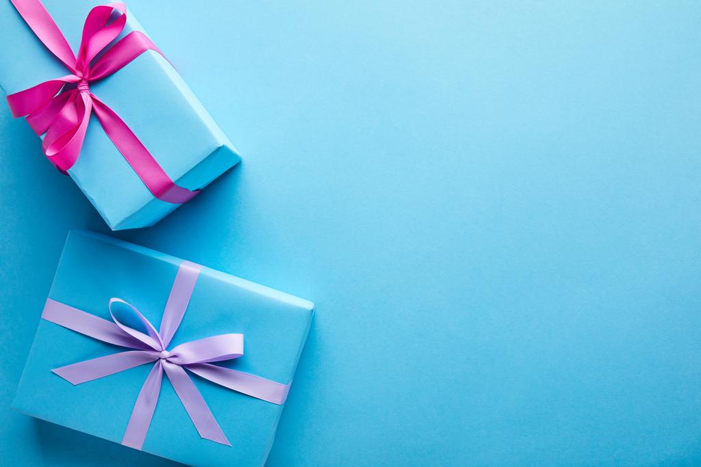 Draufsicht auf bunte Geschenkboxen auf blauem Hintergrund mit Kopierraum - Foto, Bild